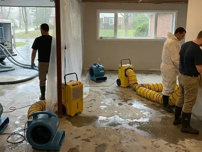 Workers arranging drying equipment across a wet ground floor room