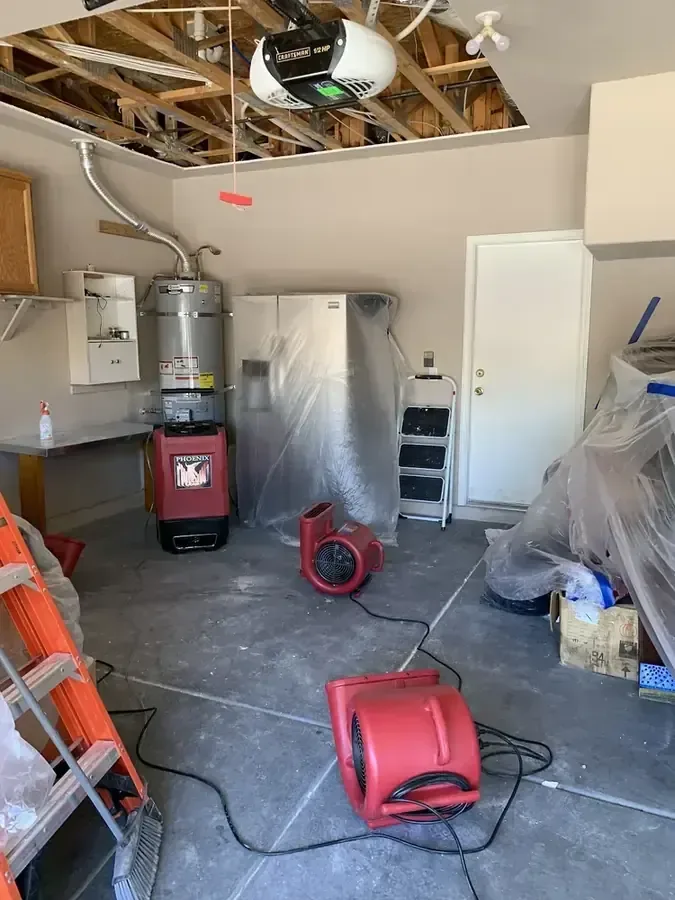 Open garage ceiling above red air movers and hoses