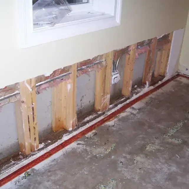 Drywall removed above a bare floor with exposed wall studs