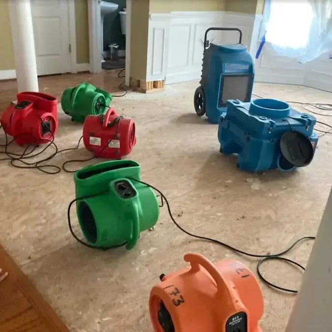 Air movers and a dehumidifier positioned across a wet subfloor