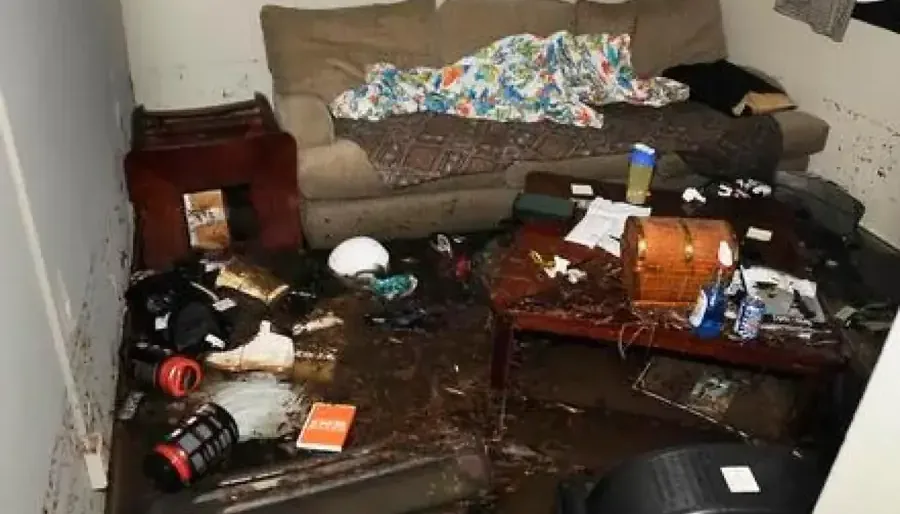 Mud and soaked belongings left in a living room by floodwater, storm flood cleanup